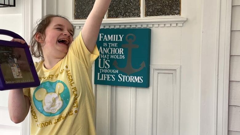 A young girl is laughing and smiling with her arm in the air. 