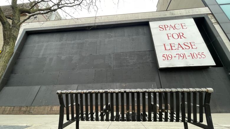 A bench in front of a boarded-up building