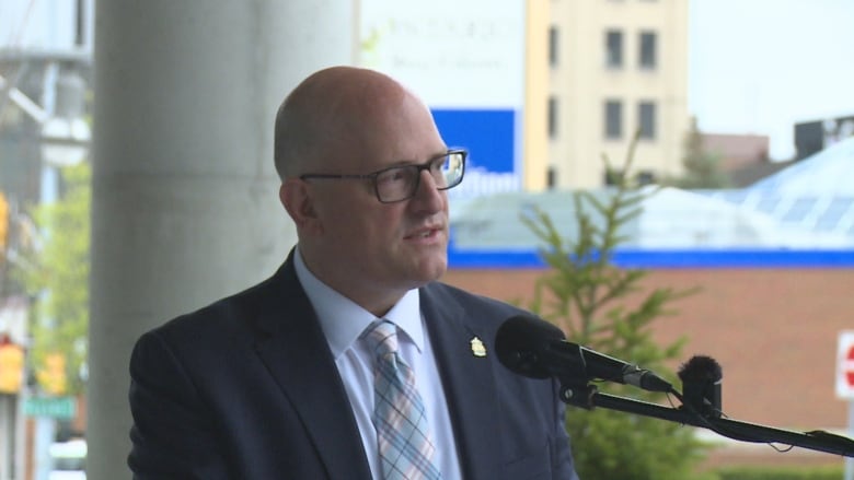 A man stands and speaks into a microphone