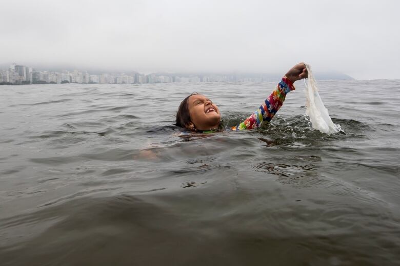 Nina Gomes recovers a discarded plastic bag from ocean waters, near Copacabana beach in Rio de Janeiro, Brazil, in March 2024.