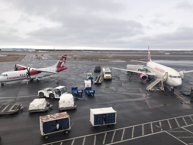 Many planes and trucks outside the airport