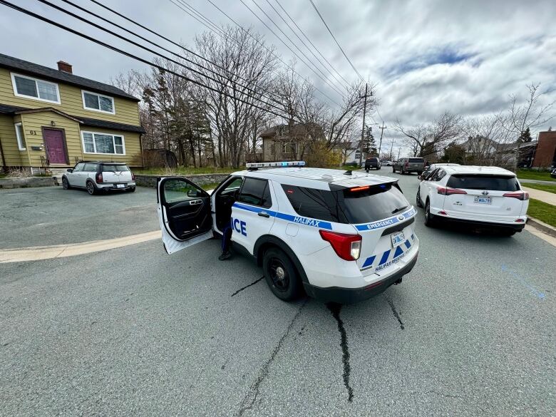 A Halifax Regional Police vehicle with its door open with other police vehicles in the background on a residential street.