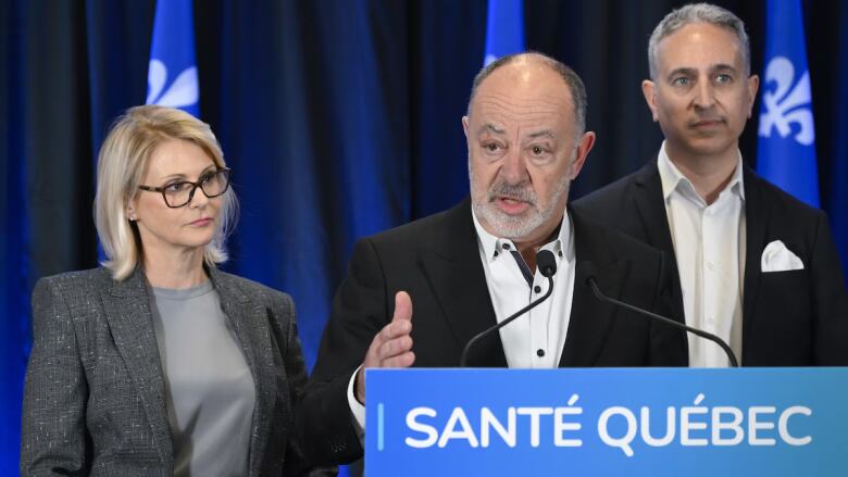 Three people stand at a podium.