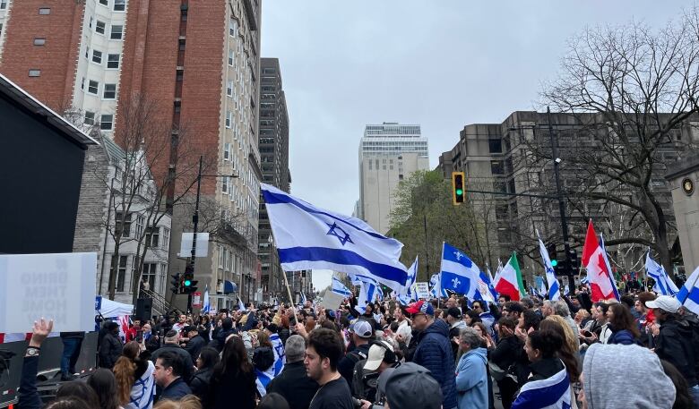 people waving Israel flags fill a downtown street