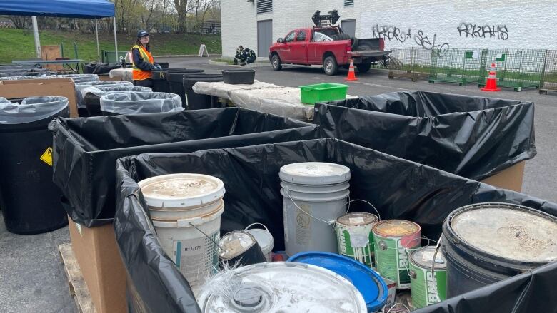 trash bins containing paint and a city worker wearing an organge vest 