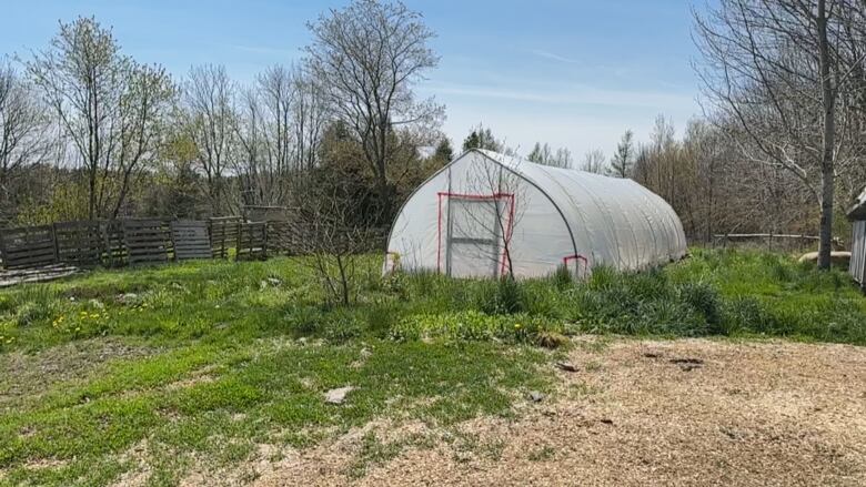 A photo of a farm. In the centre is a barn, which is covered by a white tent, marking it off limits. 