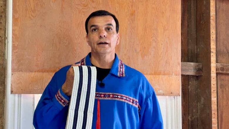 Man holding 2 row wampum belt.