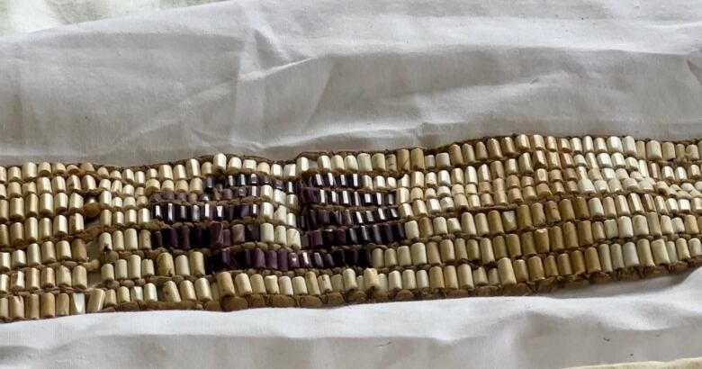 Wampum with a circle of purple beads surrounded by white beads.