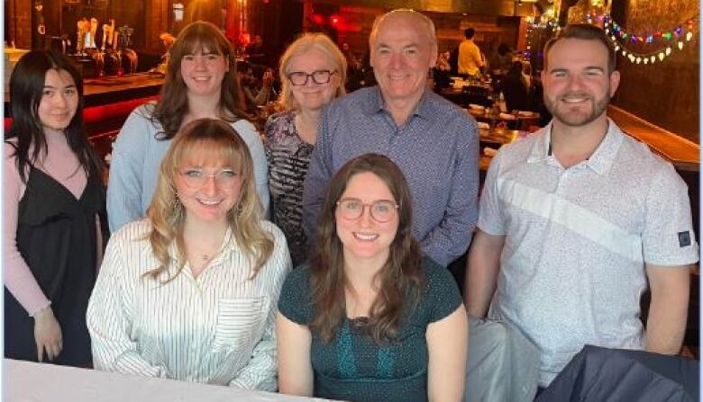 Several people smile for the camera with a restaurant behind them 