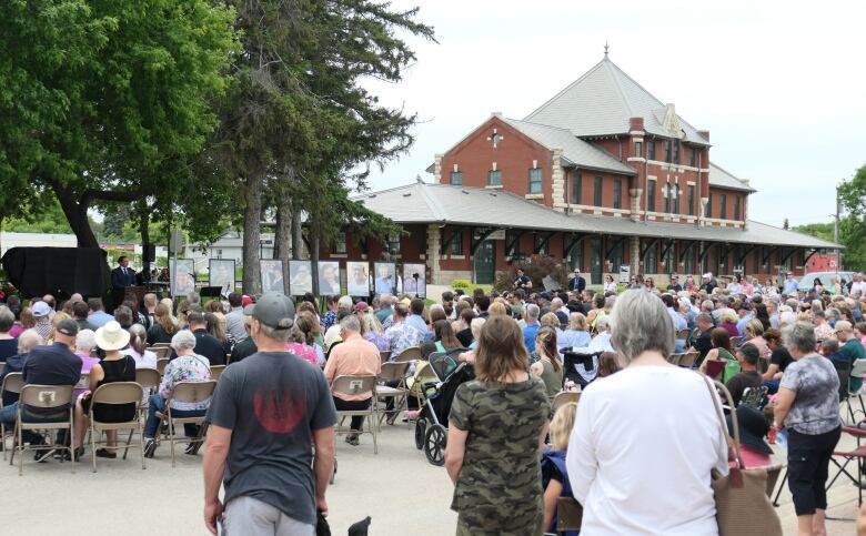 A crowd looking toward a man standing behind a podium.