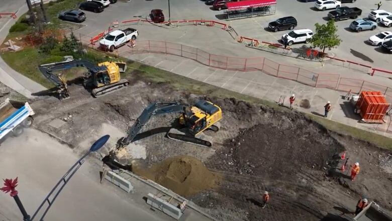 an aerial view of a construction site. heavy machinery is moving dirt over an excavation site.