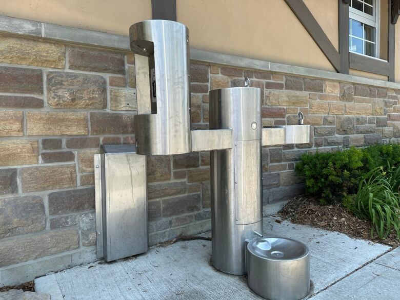 A silver water fountain with multiple spots to spew water, including a bottle refill station and a pet bowl.