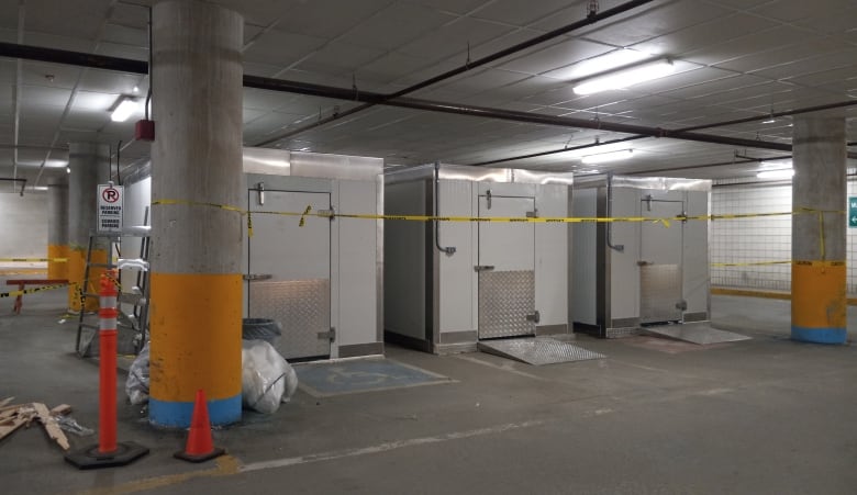 Three freezer units in a low ceiling underground parking lot.