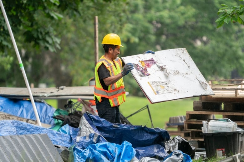 A man throws a sign into the trash. 