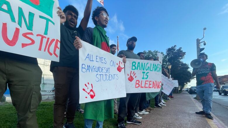 A group of people hold signs and chant outdoors.