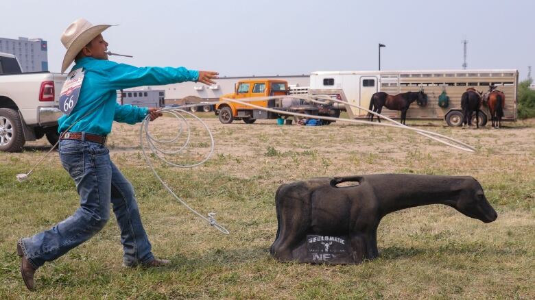 A little boy practice roping with a fake cow.