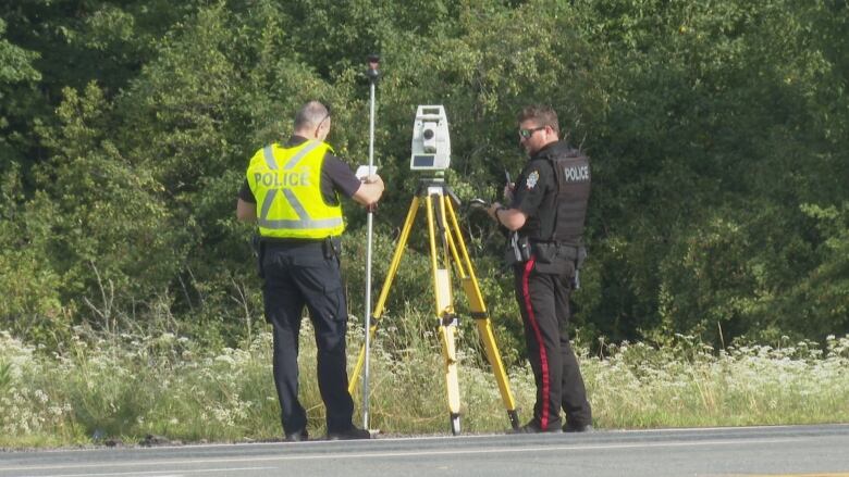 Police officers using collision reconstruction intruments.