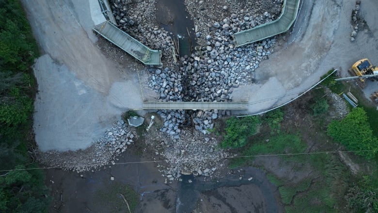 An aerial image of a washed out bridge, with a temporary walkway built across.