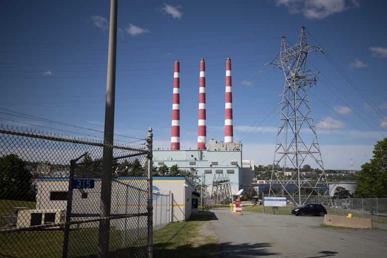 Three white-and-red striped smokestacks surrounded by power transmission lines and industrial buildings.