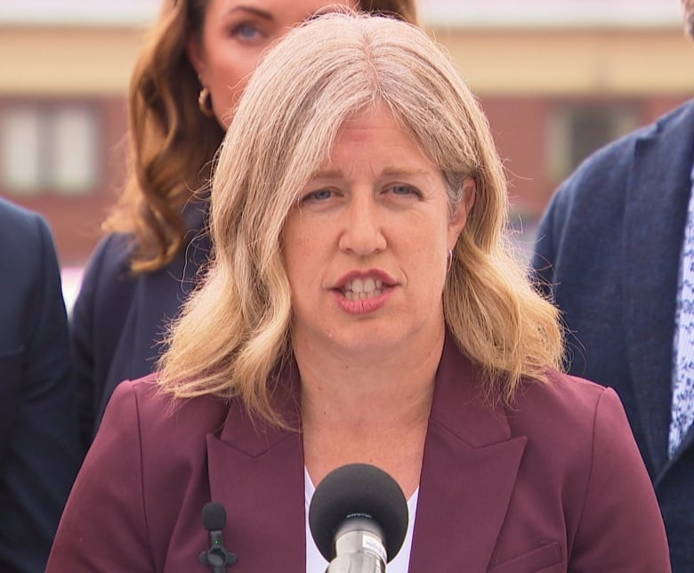 A woman with blond hair speaking into a microphone