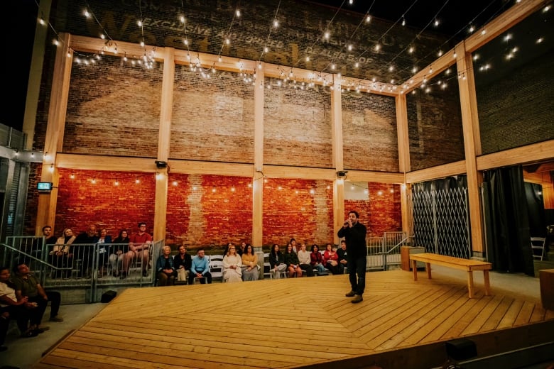 A man in black with microphone performing on a stage.