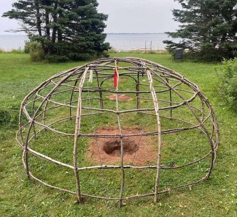 Skeleton of a sweat lodge with pit in middle.