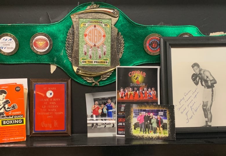 A boxing championship belt, photos and other memorabilia hanging on the wall in a gym.