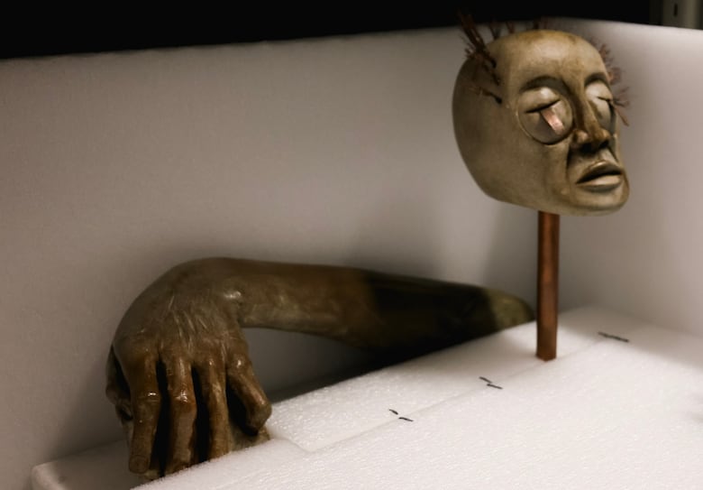 Sculpture of a head and hand on display in a museum collections tray 