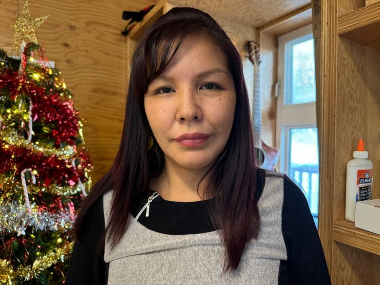 Young woman poses in front of christmas tree in common area in on the land camp