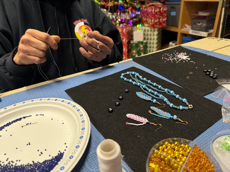 hands can be seen making beaded earrings