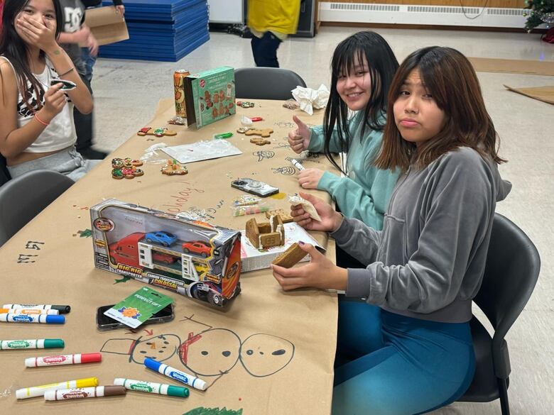 A group of girls work on gingerbread houses.